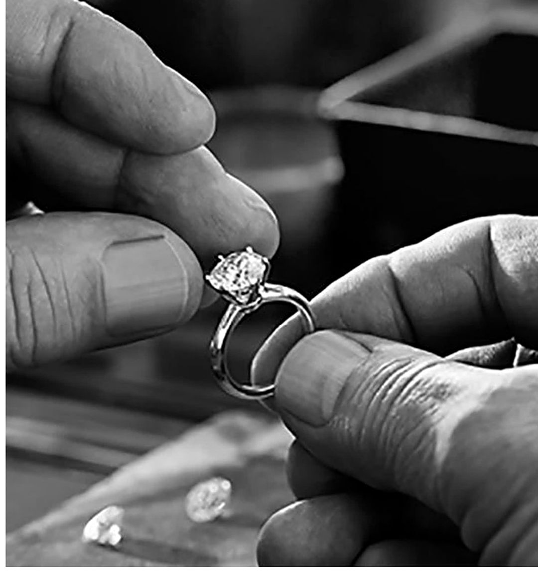 A jeweler holding a finished diamond ring at the VT Gems workbench
